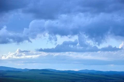 Rain clouds over distant hills at sunset. Фото