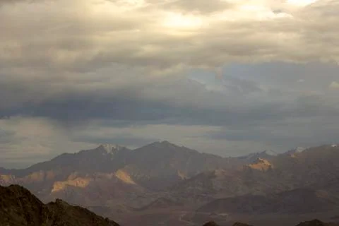 Rain clouds over a mountain valley with snowy peaks Stock Photos