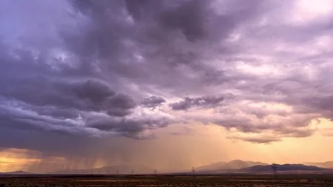 Rain clouds releasing distant precipitation over a desert at sunset Stock-Footage 341329235