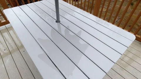 A rain covered garden table with a closed parasol reflected on the surface. Stock Footage 116103568