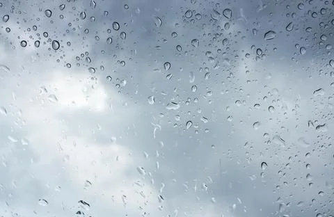 Rain-covered window with scattered droplets and soft light diffusion. Stock Photos