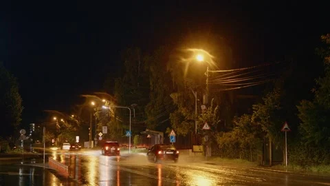 Rain creates puddles on a street while cars drive through rushing water Stock Footage 318821454