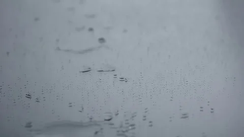 Rain dripping on a mirror with big spalshing droplets and air bubbles Stock Footage 76909215