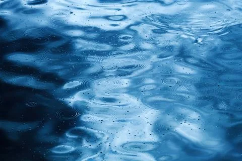 Rain drop circular pattern on rippled blue water surface, raindrops circles.. Foto stock
