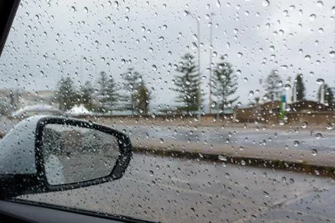 Rain droplets on a car side window, looking out to defocused street Stock Photos