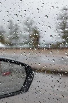 Rain droplets on a car side window, looking out to defocused street Stock Photos
