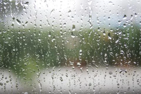 Rain droplets create a serene view on a windowpane Stock Photos