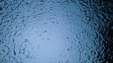 Rain droplets falling on water surface creating concentric circles Stock Photos