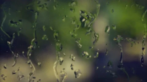 A Rain droplets sliding down glass window with rack focus of outdoors Video stock 155301729