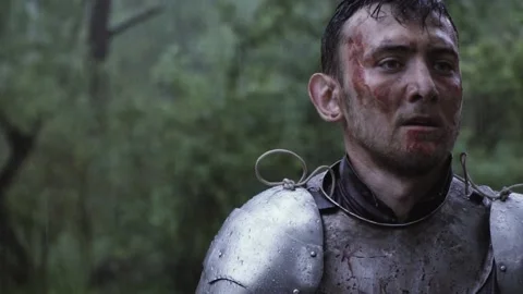 Rain drops are falling on the armor of a medieval knight with blood on his face Stock Footage 138425009
