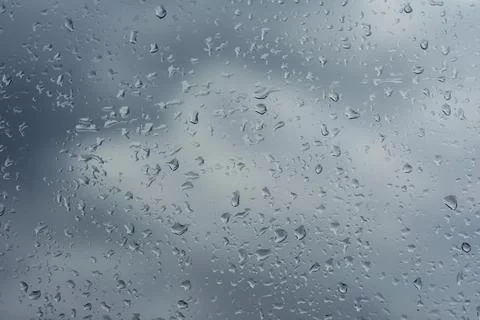 Rain drops are visible on a window glass, creating a textured pattern and a m Stock Photos