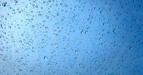 Rain drops on blue glass window background Stock Photos