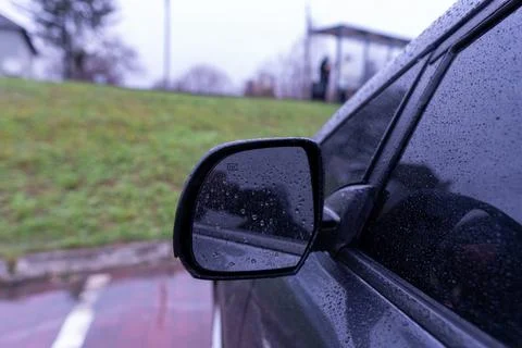 Rain Drops on Car Mirror While Parked Near a Bus Stop on a Cloudy Day in a .. Stock Photos