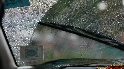 Rain drops on car wind shield with wiper Stock Photos