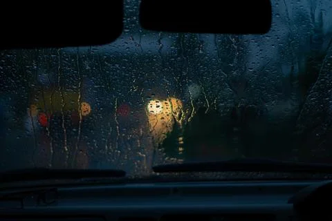 Rain drops on car window with light bokeh, rainy season abstract background. 库存照片