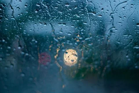 Rain drops on car window with light bokeh, rainy season abstract background. 库存照片