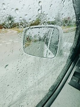 Rain Drops on Car Window with Side Mirror View of Road Fotos Stock
