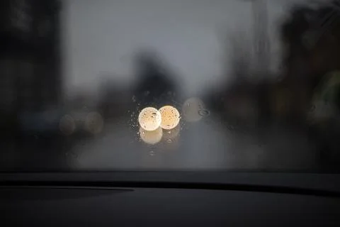 Rain drops on a car windshield with blurred lights in the background during.. Stock Photos