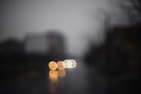 Rain drops on a car windshield with blurred street lights in the background Stock Photos
