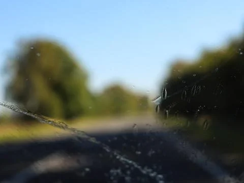 Rain drops on a car windshield while driving on a country road in the Stock Photos