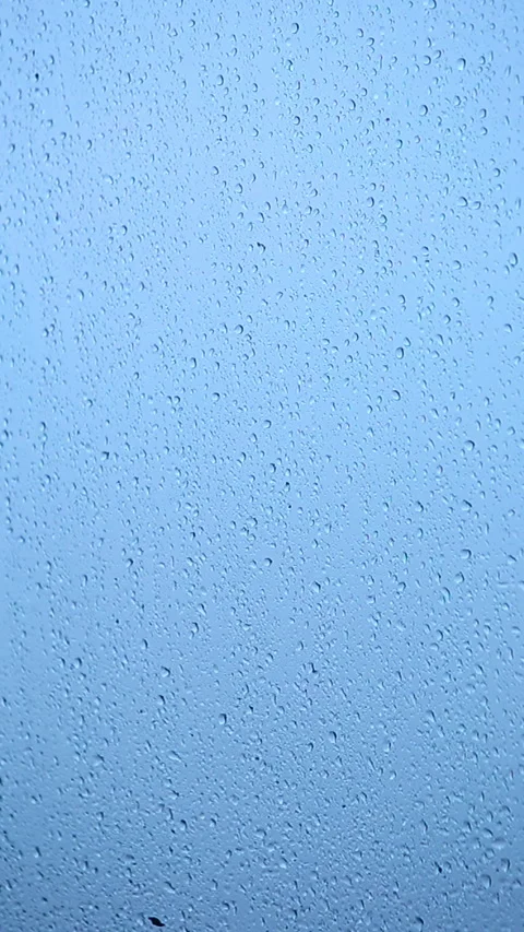 Rain drops collect on a window during a rainy day in the morning light Stock Footage 332273898