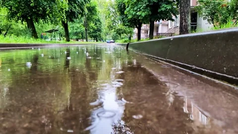 Rain drops create ripples on surface of large street puddle reflecting vibrant Stock Footage 344094197