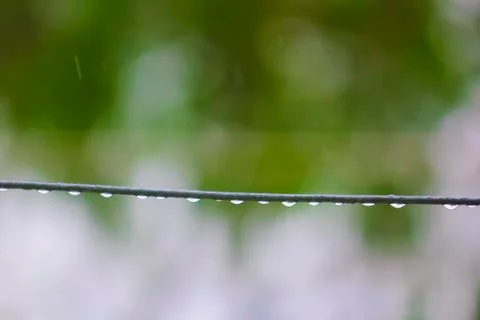 Rain drops dangling form a wire in rain. Stock Photos