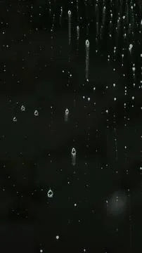 Rain drops on a dark window with water streaks Stock Photos