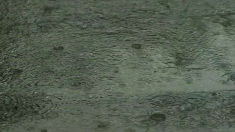 Rain drops dripping in puddle on the road. Heavy water droplets falling on Stock Footage 253409894
