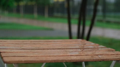 Rain drops dripping on wooden table of the open cafe terrace. Street cafe in Stock Footage 251738491