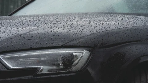 Rain drops fall on a black car. Close up shot of auto bonnet and headlight 库存影片 99002781