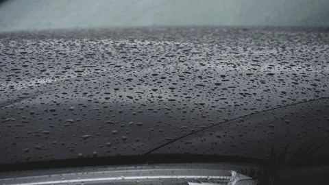 Rain drops fall on bonnet of black car. Close up shot Stock Footage 102456884