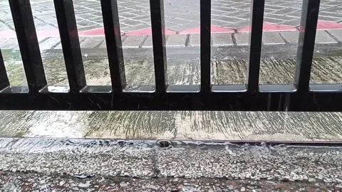 Rain drops fall on concrete and black iron fence Video stock 145569439