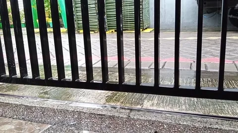 Rain drops fall on concrete and black iron fence Video stock 145569688