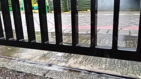 Rain drops fall on concrete and black iron fence Stock Footage 145569789