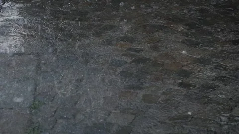 Rain drops fall down into puddles on road with pavement Stock Footage 151204471