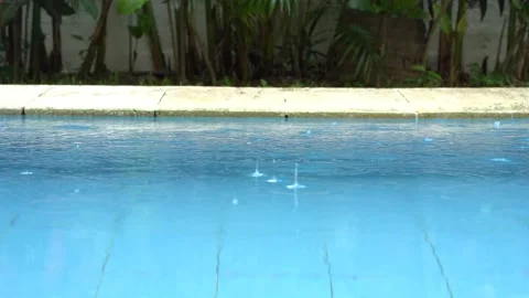 Rain drops fall into the pool on the patio Stock Footage 227455254