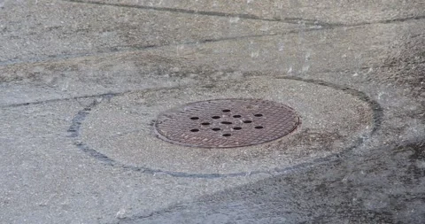 Rain drops fall on round metal manhole cover on wet asphalt street outdoors Stock Footage 340318364