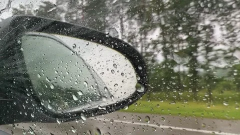 Rain drops fall on the side window and mirror of a car. Reflection of side-view Video stock 244804929