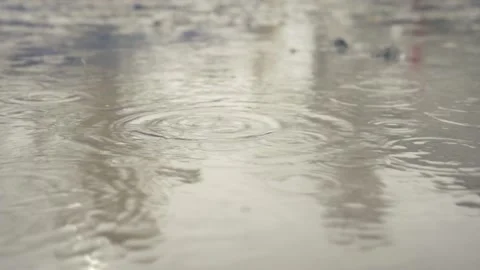 Rain drops fall in slow motion into a muddy puddle on a country street. Footage Stockbeeldmateriaal 144255104
