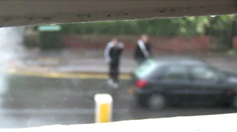 Rain drops fall on window sill,  people cross the road - slowmotion Stock Footage 8556314
