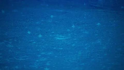 Rain drops falling on blue pool water Stockbeeldmateriaal 339469900