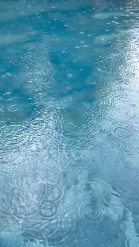 Rain Drops Falling on Blue Swimming Pool Water Surface Creating Ripples Vídeos de archivo 327047818