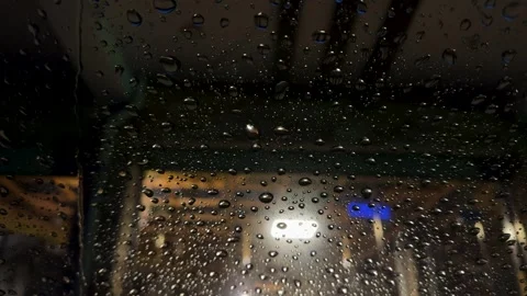 Rain drops falling on a car windscreen in winter at night Stock Footage 326239816