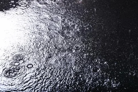 Rain drops falling down against dark background Stock Photos