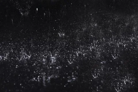 Rain drops falling down against dark background Stock Photos