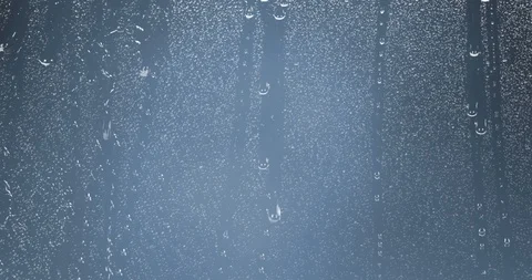 Rain drops falling down on glass blue background, water droplets on window Vidéo 86592382