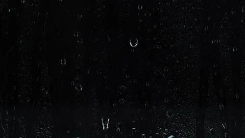 Rain drops falling down on window over black background, raining at night, 4K Stock Footage 142558310