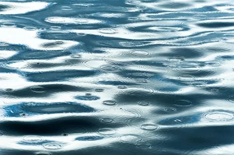 Rain drops falling on lake surface Stock Photos