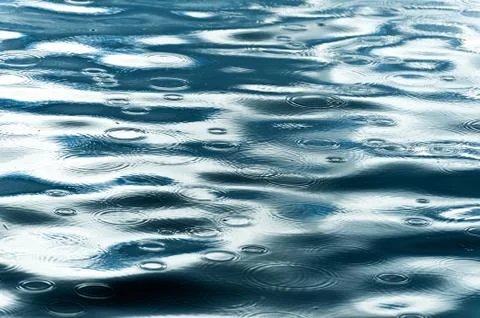 Rain drops falling on lake surface Stock Photos